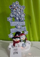 Front view of ceramic snowmen decoration with lighted snowflakes and sign