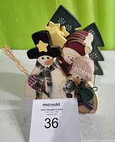 Front view of the wooden snowman coaster set in holder with visible snowman faces and decorative stars and trees