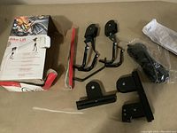 Photo showing all components of the bike lift including two black hooks, mounting bracket, straps, manual, and product box.