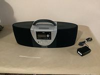 Full front view of Clarion Sirius boombox with power adapter placed beside it on table.