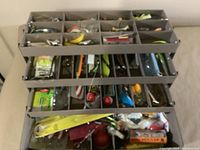 Top-level view of the fishing tackle box fully loaded with various fishing lures and accessories organized in compartment trays.