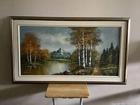 Front view of the large framed oil painting showing the landscape with birch trees, pond, and mountain.