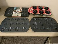 Four piece bakeware set showing various baking pans with detailed shapes on a brown surface