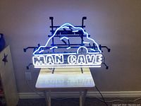 Neon sign lit up, showing 'MAN CAVE' text and blue mountain design clearly.