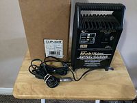 Overall view of the Mobiline battery charger with cables and box on table.