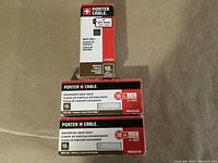 Three boxes of Porter Cable galvanized brad nails arranged on a surface. One upright 2 inch box and two flat 1.5 inch boxes.