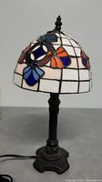 Full view of the Tiffany style stained glass lamp showing floral design and metal base.