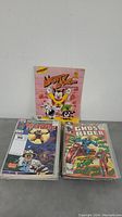 Photo showing one Mighty Mouse magazine standing upright behind two stacks of comic books featuring Wolverine and Ghost Rider covers.
