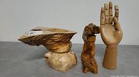 Photo showing all three sculptures: a hollowed maple tree section, a standing bear sculpture, and a flexible wooden hand.