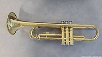 Full side view of the Yamaha brass trumpet showing the bell, tubing, and valves.