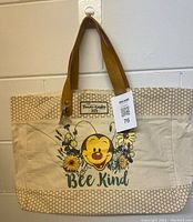 Front view of Disney Bee Kind tote bag showing smiling bee with flowers and text 'Bee Kind' and 'Flower Garden 2022'.