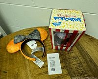 Photo of the Halloween-themed Minnie Mouse ears headband next to the Vinylmation Popcorn collectible box on wooden surface