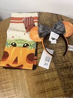 Three Halloween-themed Grogu towels folded displayed with a Grogu ears headband with a large black bow, all with original tags and pet-friendly home use.