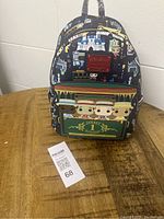 Front view of the mini backpack showing colorful Disney Parks-themed print with characters and castle, train detail on front pocket, and Loungefly logo patch.