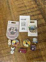 Disney trading pins laid out on a wooden surface with the seller's lot number card visible. Pins include 2 on original cardbacks and 7 loose pins of various characters and styles.