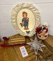 Full view of vintage Christmas decor including the wall hanging, sled, star tree topper, and Santa doll.