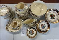 Overview of lot showing multiple china pieces including pitchers, bowls, plates with floral and gold patterns and central medallion scenes