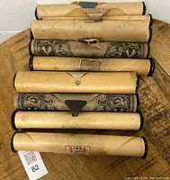 Nine vintage player piano rolls laid on a wooden surface showing their labels and clips, with some paper edges torn or aged.