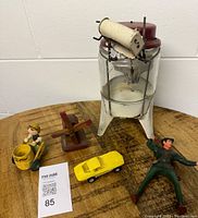 Full lot showing vintage toy washing machine, Peter Pan figure, yellow toy car, wooden windmill and wood carving on round wooden table