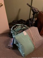 Inflatable dinghy boat packed and folded in a basement room, along with other items like the motor and boxes.