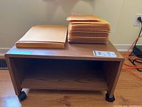 Photo showing wood grain cart on small wheels with two stacks of envelopes on top: a larger stack of bubble mailers and a smaller stack of Kraft envelopes