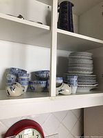 Two shelves of Elaine China West German porcelain dishes featuring blue floral patterns including tea cups, mugs, plates and small pitchers.