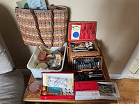Photo showing several baskets and bins containing sewing supplies including an electric scissors box and assorted crafting tools.
