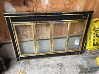 Full view of Glassfyre fireplace screen showing black metal frame with gold trim and two glass paneled doors