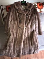 Full front view of the brown mink fur coat laid flat showing collar, sleeves and overall length.