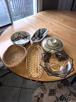 Overview of all items on wooden table near window: 2 baskets, 3 pottery pieces, glass bowl