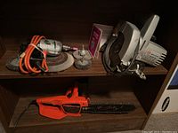 Shelf with multiple tools including Remington Powercutter chainsaw, Black & Decker circular saw, unbranded drill and polishing attachments
