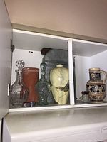 Wide view showing all vases and decanters in a white shelf compartment