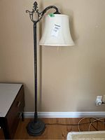 Full view of vintage floor lamp standing 59 inches tall against a beige wall, showing metal stand and attached fabric shade with label.