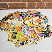 Scattered Pokémon cards from the lot showing various character, energy, and trainer cards with different colors and designs.