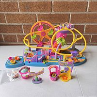 Wide view of the vintage Polly Pocket amusement park set on table showing Ferris wheel, rides, and other playset features in bright colors.