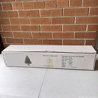 White rectangular cardboard box containing a Sears branded artificial Christmas tree, displaying distribution center and supplier information.