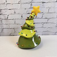 Photo showing vintage ceramic crooked Christmas tree with multiple colorful bulb lights and yellow star on top, not lit.