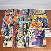 Group of vintage comic books including Blue Devil, Hawkman, Flash, and more fanned out on table.