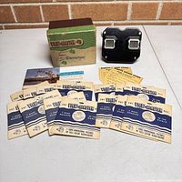 View-Master viewer, box, twelve reels, informational materials arranged together showing lot contents.