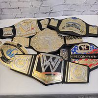 Lot of six WWE wrestling championship belts displayed together, showing all belts in one photo for overview.