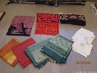 Top-down photo showing all assorted textiles and linens laid flat on a surface, displaying different colors and patterns including African motifs and embroidered linens.