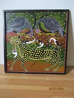 Full view of framed acrylic folk art painting showing a leopard with yellow spots and tropical birds in green brown background.