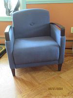 Front view of the club chair showing the blue upholstery and espresso wood arms and legs.