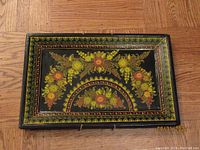 Full view of a rectangular black lacquer tray with detailed floral hand-painted decoration in warm colors