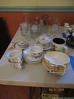 Various glassware, cups, saucers, natural shell dishes, and small plates on a table