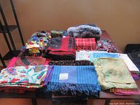 Wide view of the entire lot including various scarves, wristbands, hats, and tapestry belt on a table.