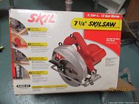 Box showing Skilsaw 7 1/4" circular saw model 5400-01 with 2.3 HP, 12 AMP motor info and branding.