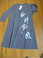 Full view of a long women's dress in gray with white floral design, new with tags