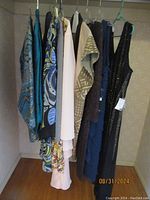 Photo showing seven women's formal dresses on hangers in closet, various patterns and colors including the black sleeveless metallic striped dress