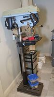 Front view of drill press with bits on worktable